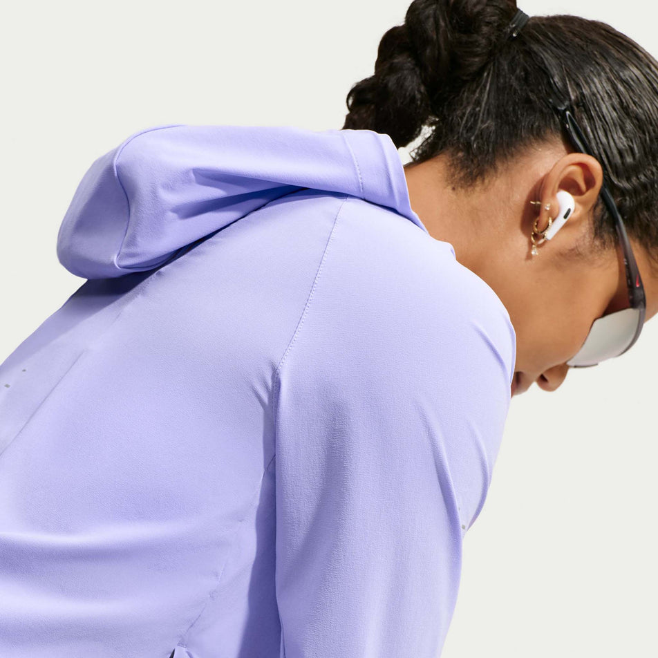 Angled view of a model wearing the Nike Women's Swift Repel Packable Running Jacket in the Purple Pulse/Reflective Silver colourway.