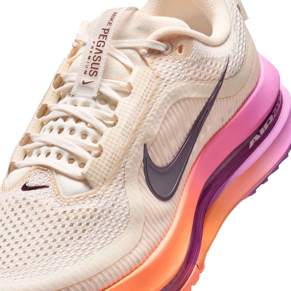 Close-up view of the upper of the left shoe from a pair of Nike Women's Pegasus Premium Road Running Shoes in the Chalk/Tattoo-Orange Pulse-Light Magenta colourway.