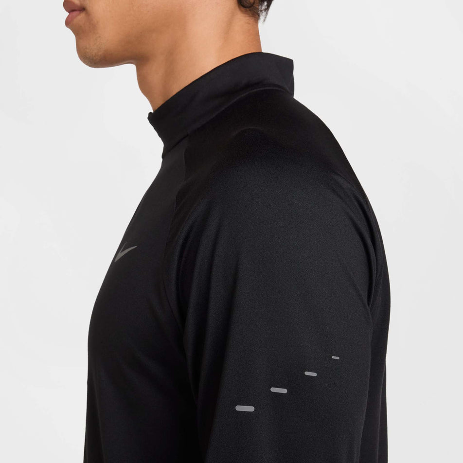 Side view of a model wearing the Nike Men's Stride Dri-FIT 1/4-Zip Running Top in the Black/Reflective Silver  colourway. (8778198876322)