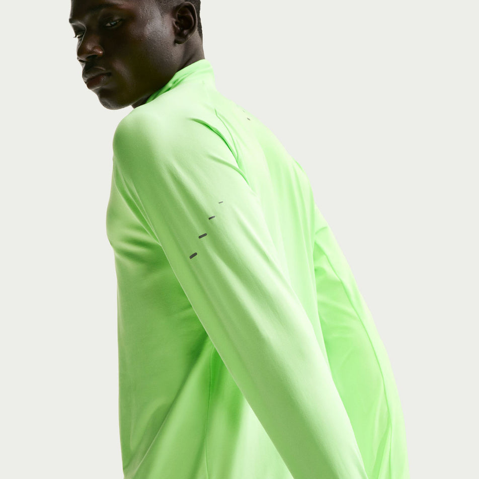 Angled view of a model wearing the Nike Men's Stride Dri-FIT 1/4-Zip Running Top in the Lime Blast/Reflective Silver colourway.