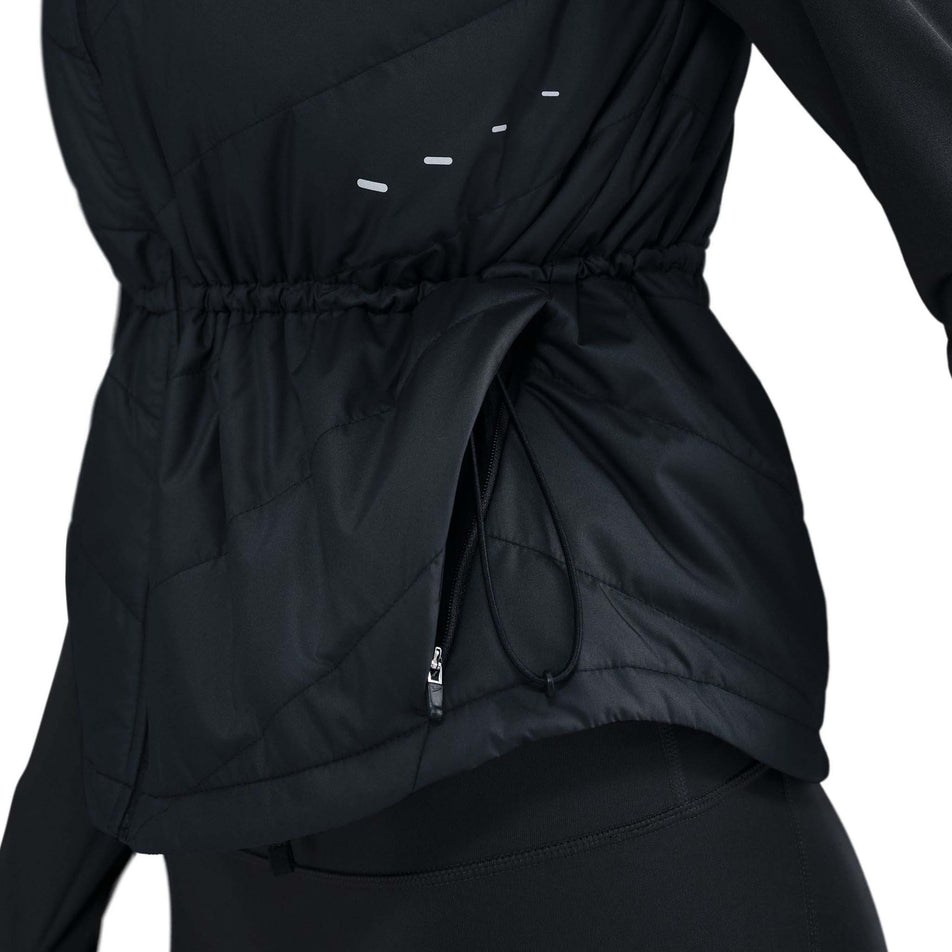 Side view of a model wearing the Nike Women's Swift Therma-FIT Running Vest in the Black/Reflective Silver colourway.