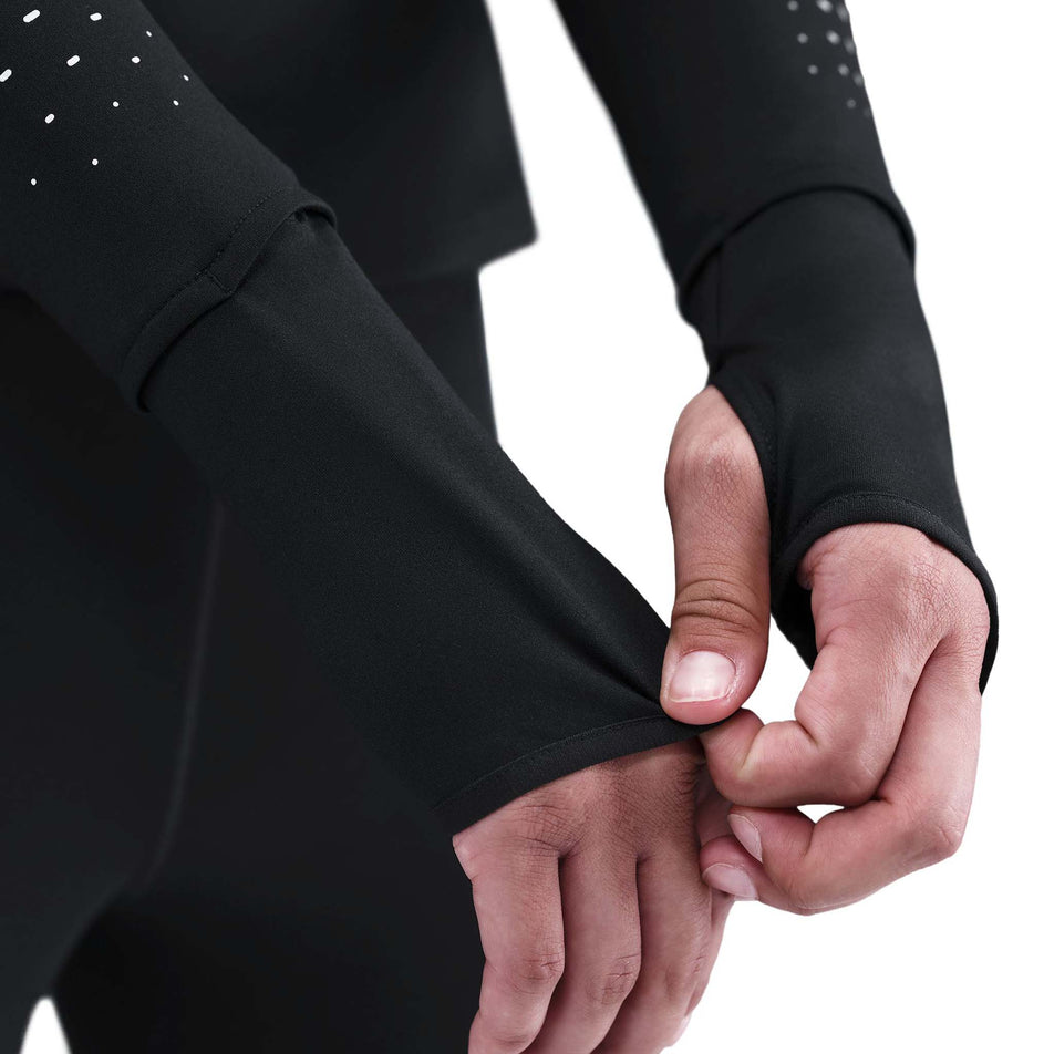 A model demonstrating the thumb-loops on the Nike Women's Swift Therma-FIT ADV 1/4-Zip Running Top in the Black/Reflective Silver colourway. (8756532904098)