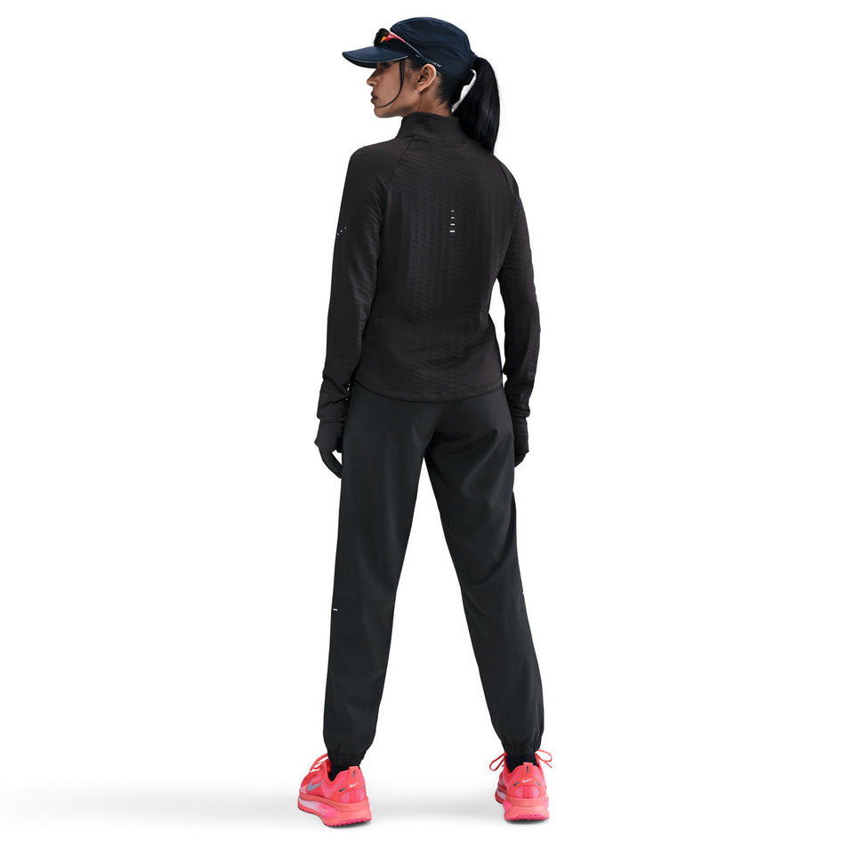 Back view of the Nike Women's Swift Therma-FIT Turtle-Neck Running Top in the Black/Reflective Silver colourway.  (8756579270818)