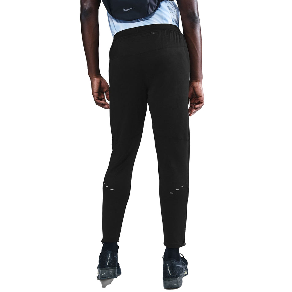 Back view of a model wearing the Nike Men's Dri-FIT Stride Knit Running Pants in the Black/Reflective Silver colourway. (8733229744290)