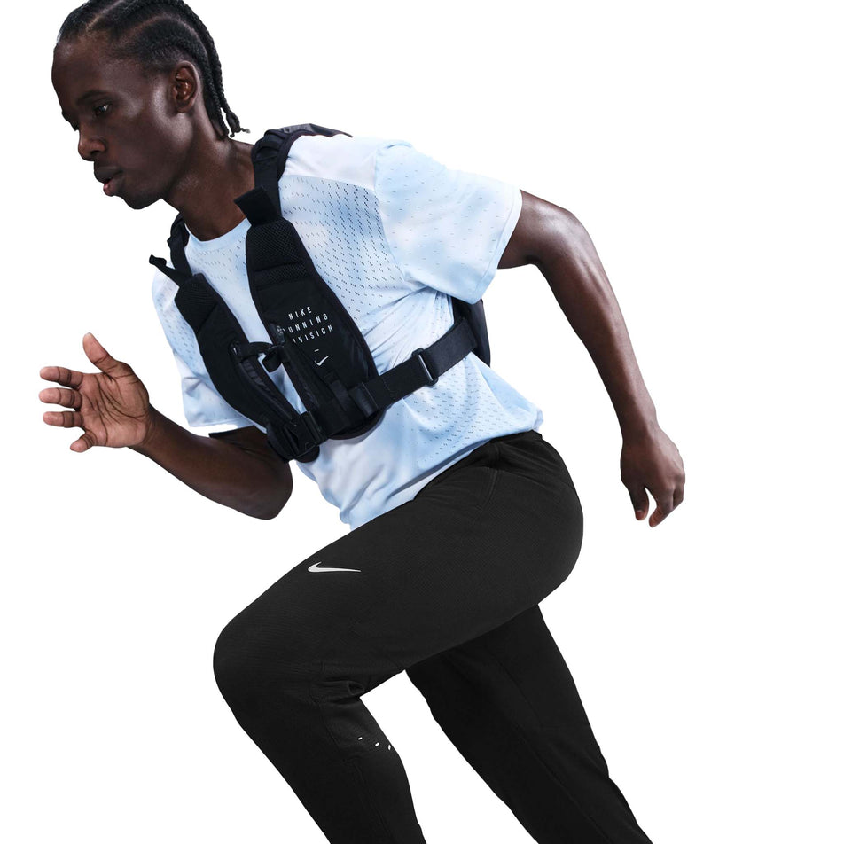 Angled view of a model wearing the Nike Men's Dri-FIT Stride Knit Running Pants in the Black/Reflective Silver colourway.(8733229744290)