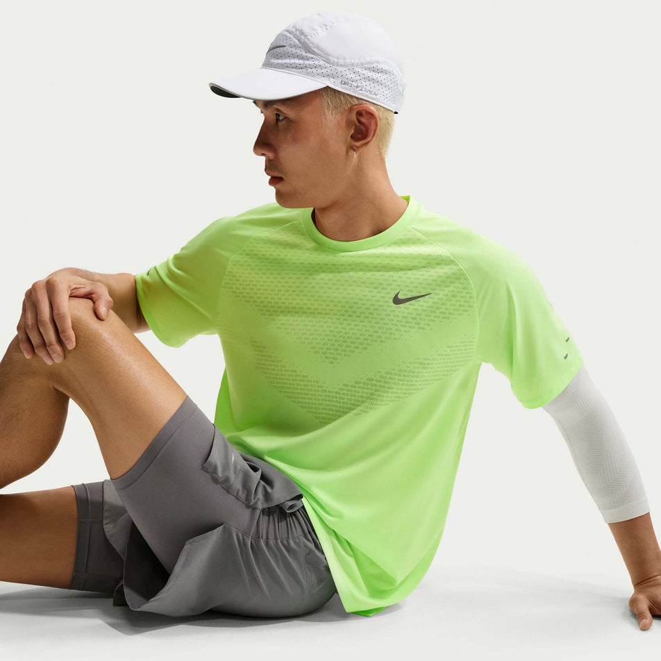 Angled view of a model wearing the Nike Men's Stride Dri-FIT ADV Short-Sleeve Running Top in the Lime Blast/Reflective Silver colourway.