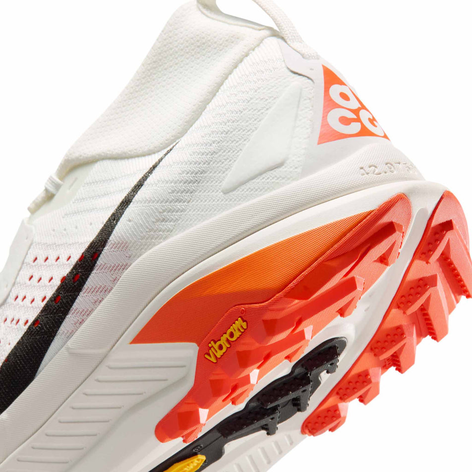 Close-up view of the rearfoot section of the left shoe from a pair of Nike Men's ACG Zegama Trail Running Shoes in the Summit White/Black-Phantom-Safety Orange colourway.