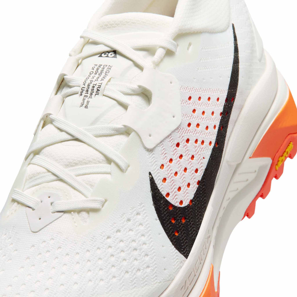 Close-up view of the upper of the left shoe from a pair of Nike Men's ACG Zegama Trail Running Shoes in the Summit White/Black-Phantom-Safety Orange colourway.