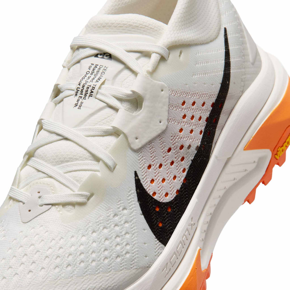 Close-up view of the upper of the left shoe from a pair of Nike Women's ACG Zegama Trail Running Shoes -in the Summit White/Black-Phantom-Safety Orange colourway.