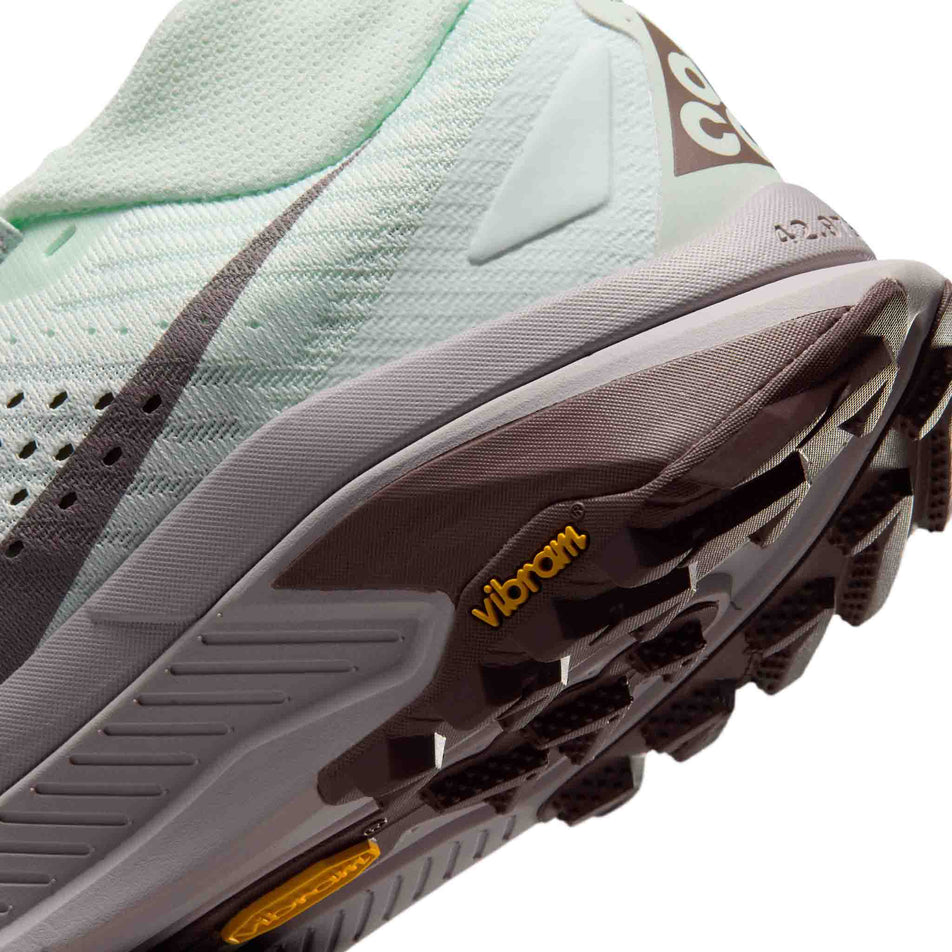 Close-up view of the rearfoot section of the left shoe from a pair of Nike Women's ACG Zegama Trail Running Shoes in the Barely Green/Silver Lilac-Tattoo colourway.