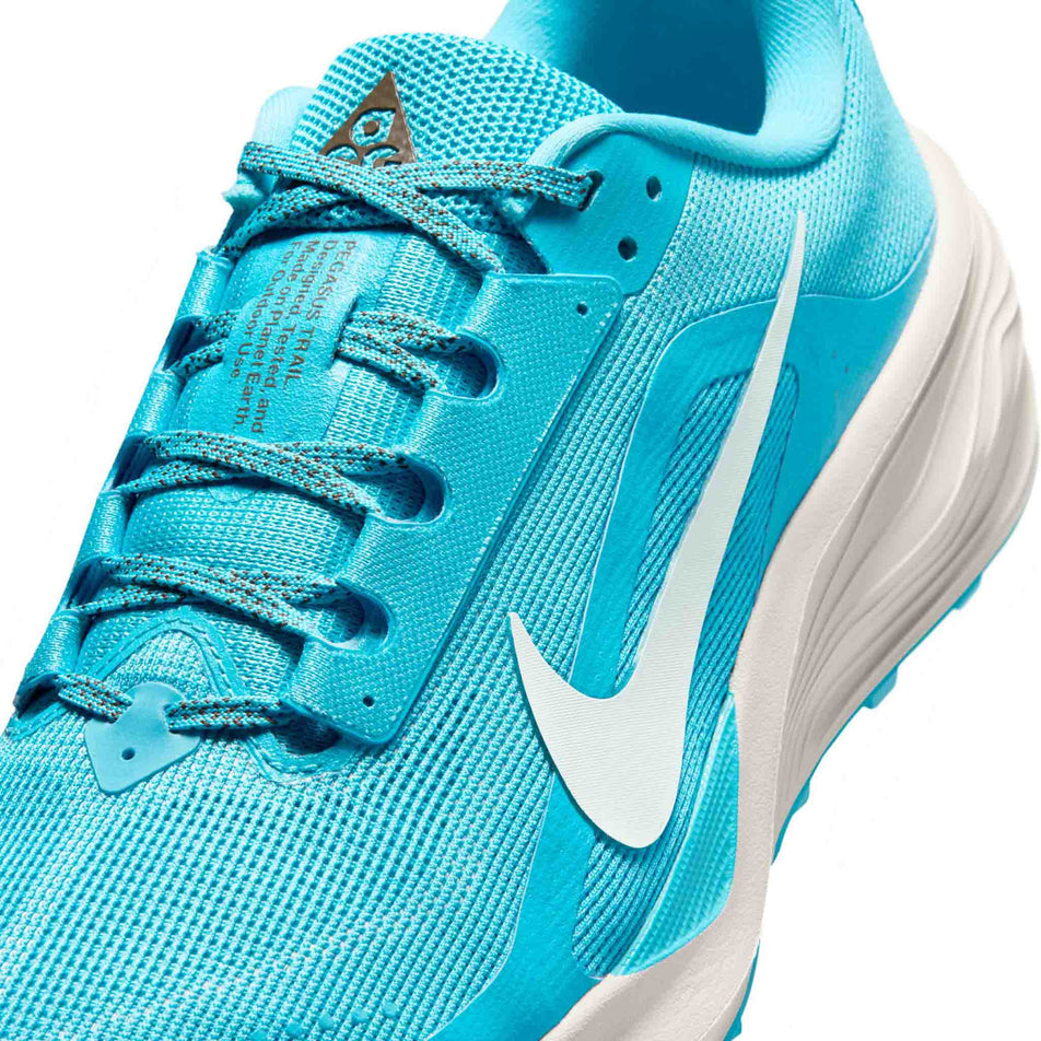Close-up view of the upper of the left shoe from a pair of Nike Men's ACG Pegasus Trail Running Shoes in the Baltic Blue/Summit White-Light Orewood Brown colourway.