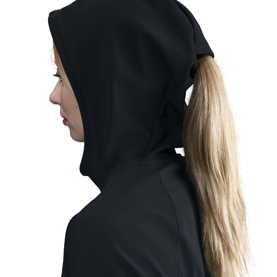 Side view of a model wearing the Nike Women's Swift Therma-FIT Running Jacket in the Black/Reflective Silver colourway with the hood up.