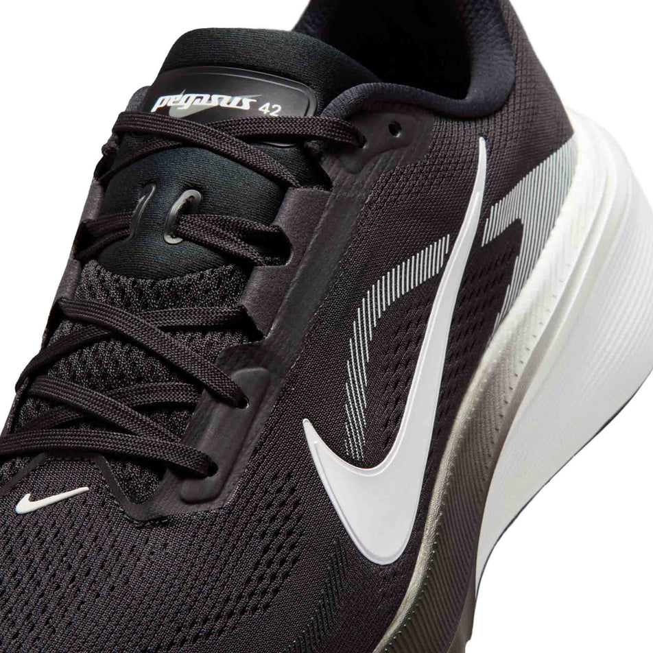 Close-up view of the upper of the left shoe from a pair of Nike Men's Pegasus 42 Road Running Shoes in the Black/White-Photon Dust colourway.
