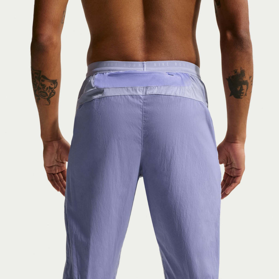 Back view of a model wearing the Nike Men's Stride Repel Woven Running Pants in the Iron Purple/Indigo Haze/Reflective Silver colourway.