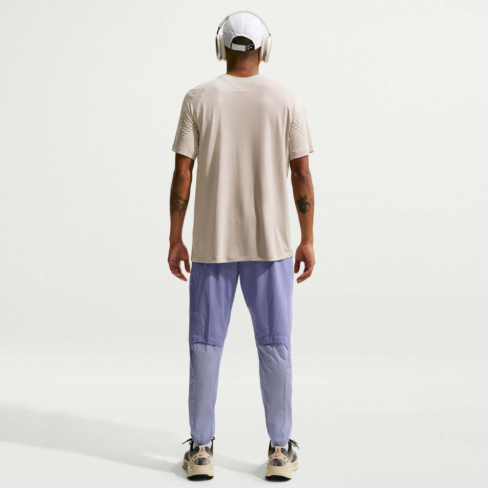 Back view of a model wearing the Nike Men's Stride Repel Woven Running Pants in the Iron Purple/Indigo Haze/Reflective Silver colourway.