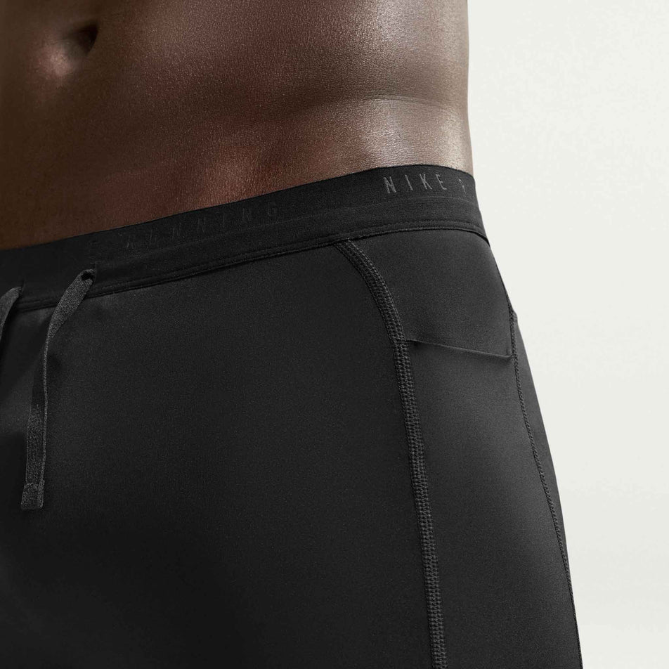 Angled view of a model wearing the Nike Men's Stride Dri-FIT 1/2-Length Running Tights in the Black/Reflective Silver colourway.
