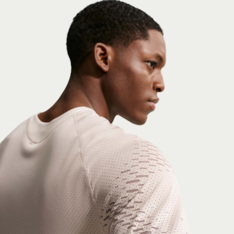 Back view of a model wearing the Nike Men's Stride Dri-FIT ADV Short-Sleeve Running Top in the Cream II/Mink Brown/Reflective Silver colourway.