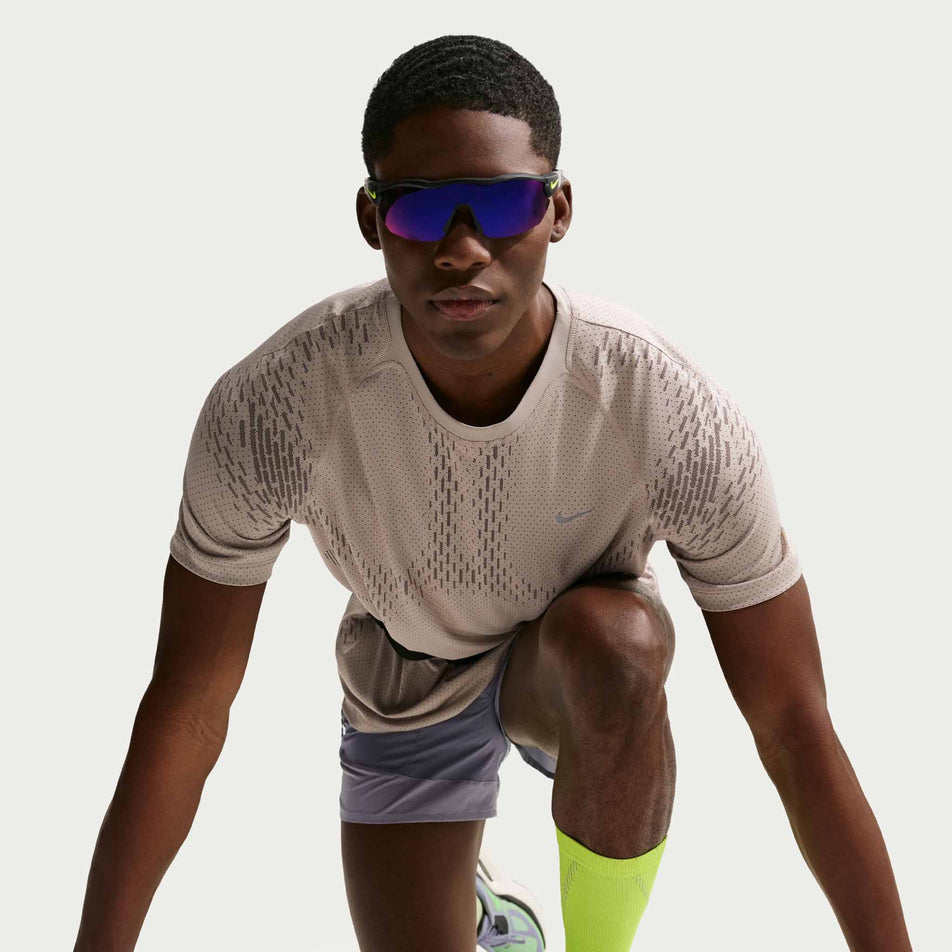 Front view of a model wearing the Nike Men's Stride Dri-FIT ADV Short-Sleeve Running Top in the Cream II/Mink Brown/Reflective Silver colourway.