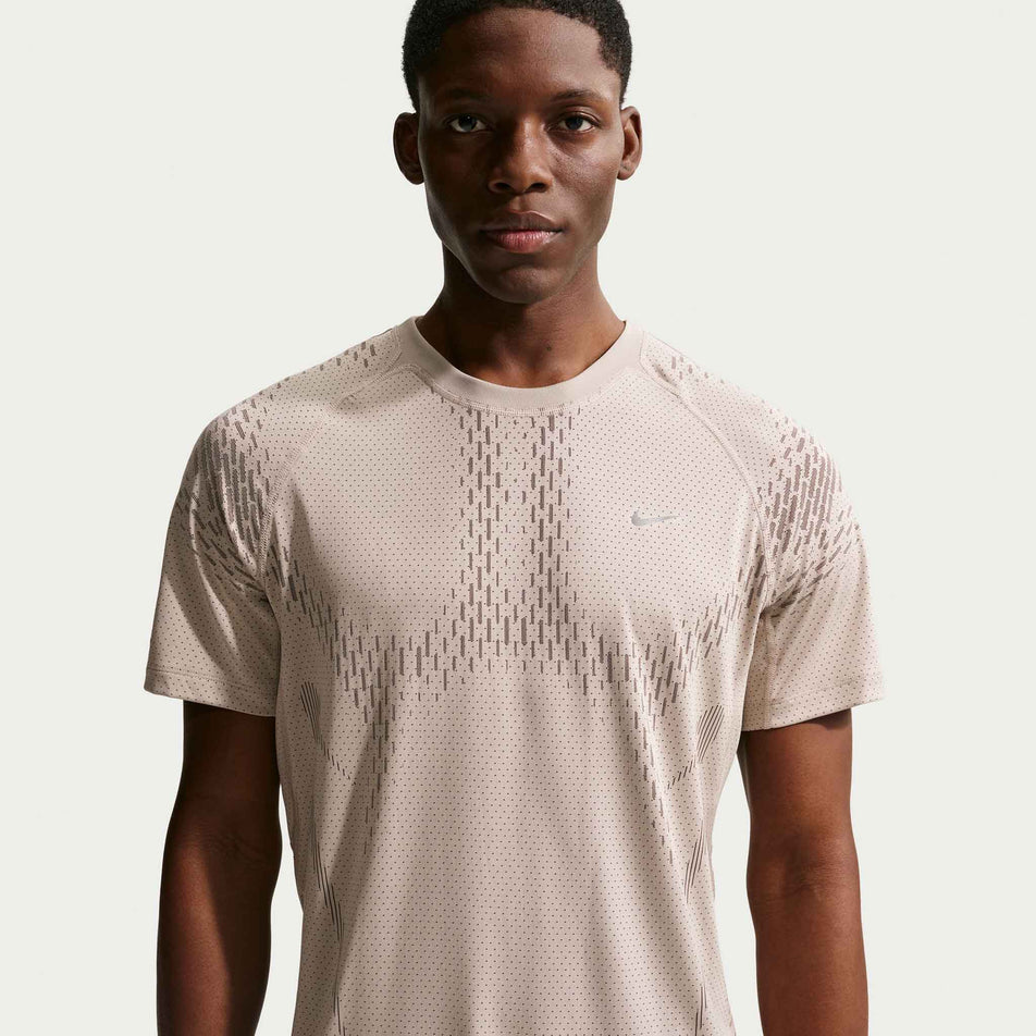 Front view of a model wearing the Nike Men's Stride Dri-FIT ADV Short-Sleeve Running Top in the Cream II/Mink Brown/Reflective Silver colourway.