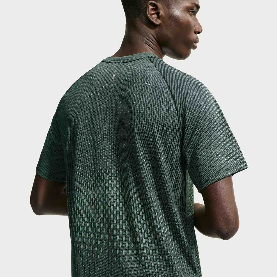 Back view of a model wearing the Nike Men's Stride Aero-FIT Short-Sleeve Running Top in the Black/Light Green Spark/Reflective Silver colourway.