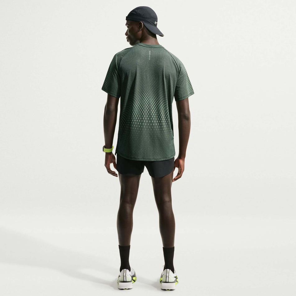Back view of a model wearing the Nike Men's Stride Aero-FIT Short-Sleeve Running Top in the Black/Light Green Spark/Reflective Silver colourway.