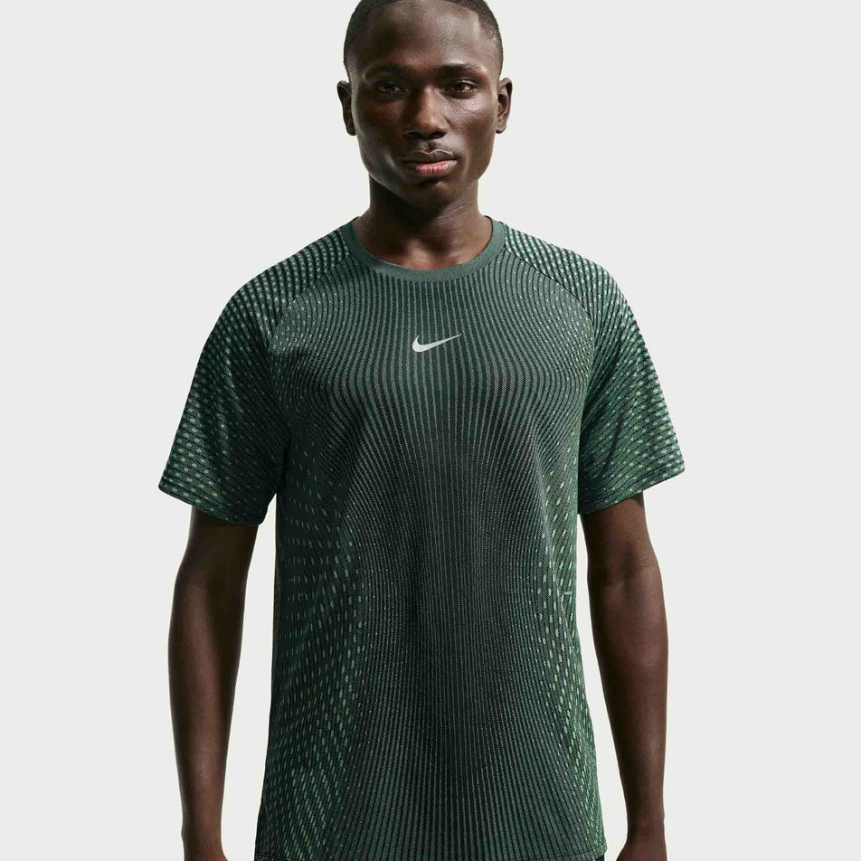 Front view of a model wearing the Nike Men's Stride Aero-FIT Short-Sleeve Running Top in the Black/Light Green Spark/Reflective Silver colourway.