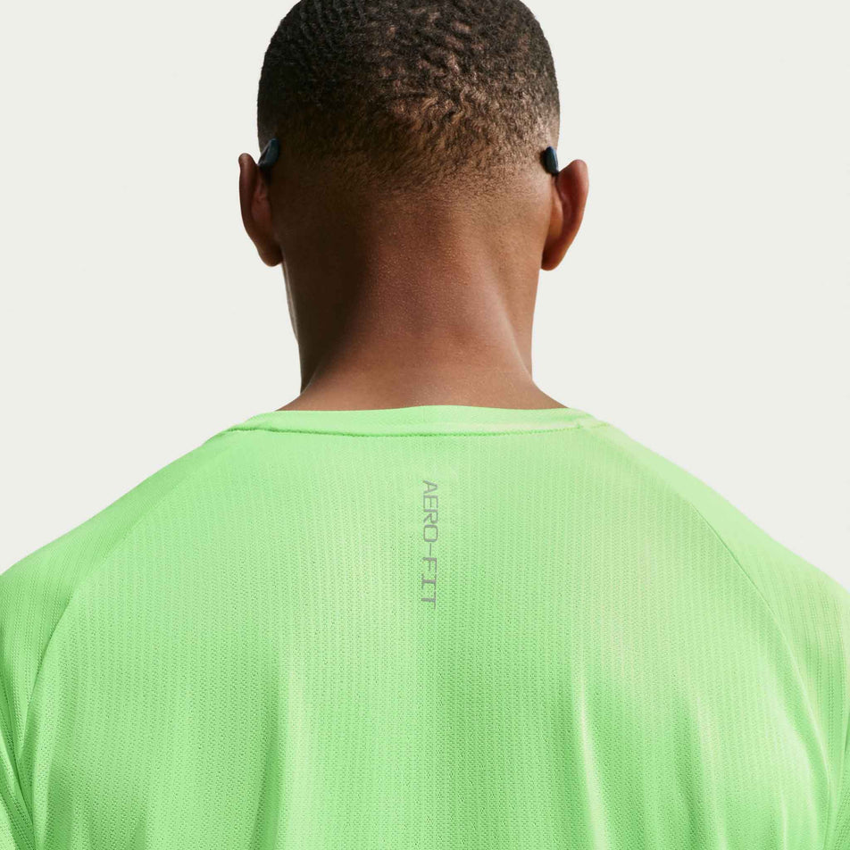 Back view of a model wearing the Nike Men's Stride Aero-FIT Short-Sleeve Running Top in the Volt/Light Silver/Reflective Silvern colourway.