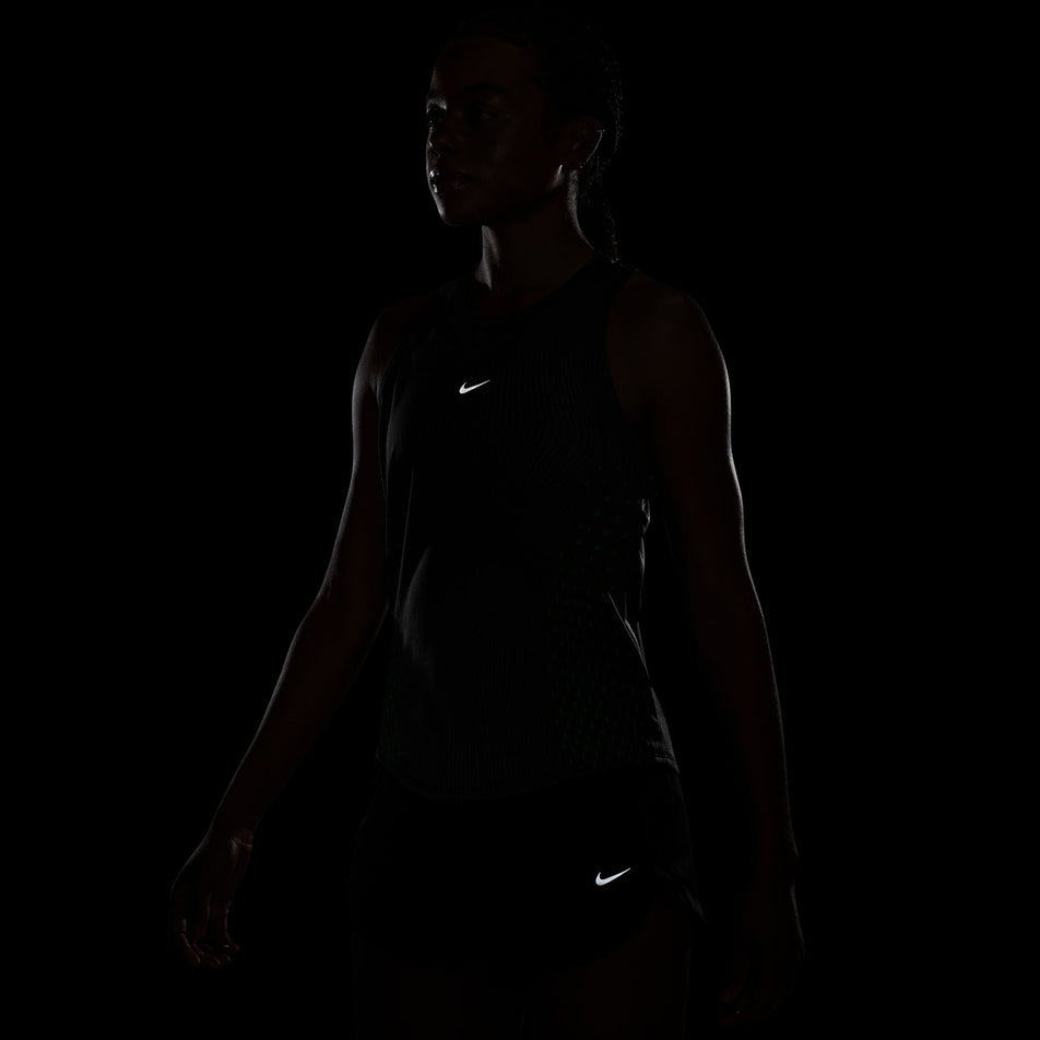 The reflective Swoosh on the front of the Nike Women's Swift Aero-FIT Running Tank Top in the Black/Light Green Spark/Reflective Silver colourway.