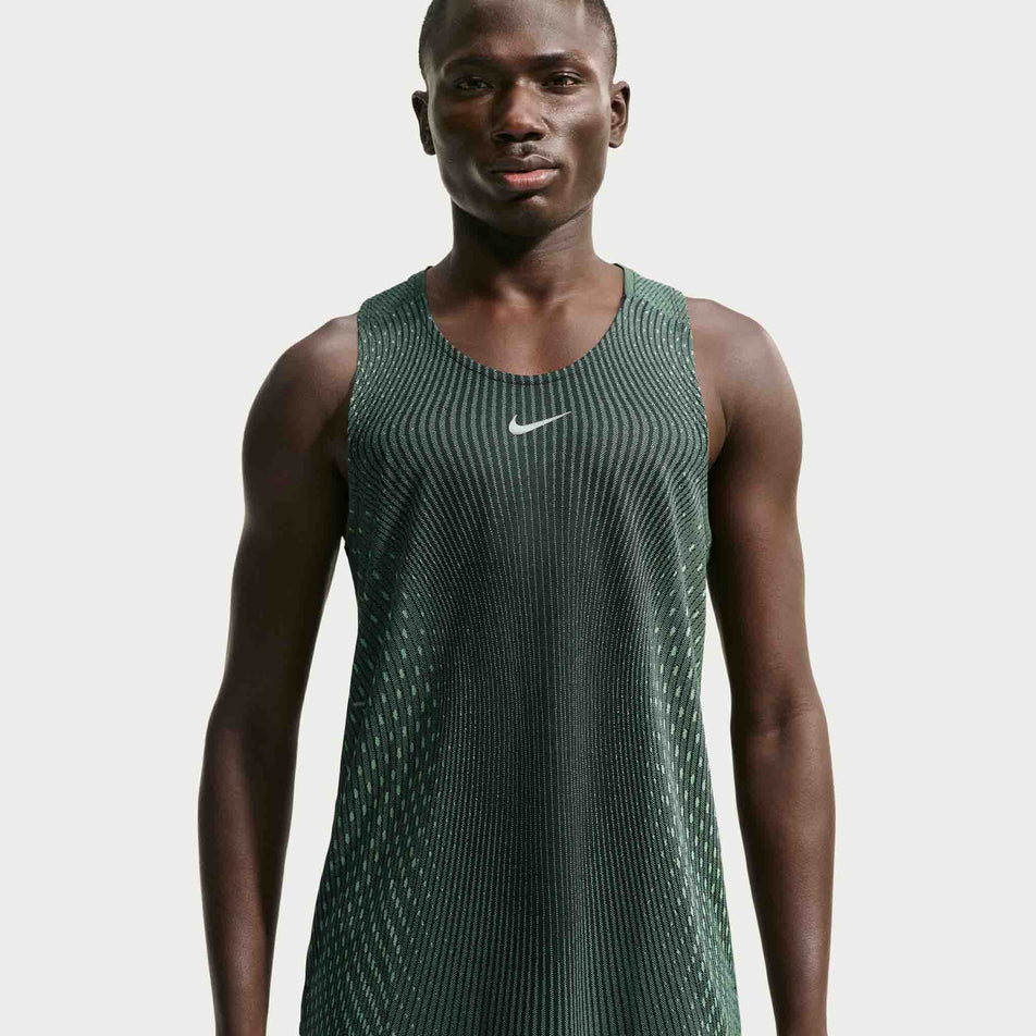 Front view of a model wearing the Nike Men's Stride Aero-FIT Running Tank Top in the Black/Light Green Spark/Reflective Silver colourway.