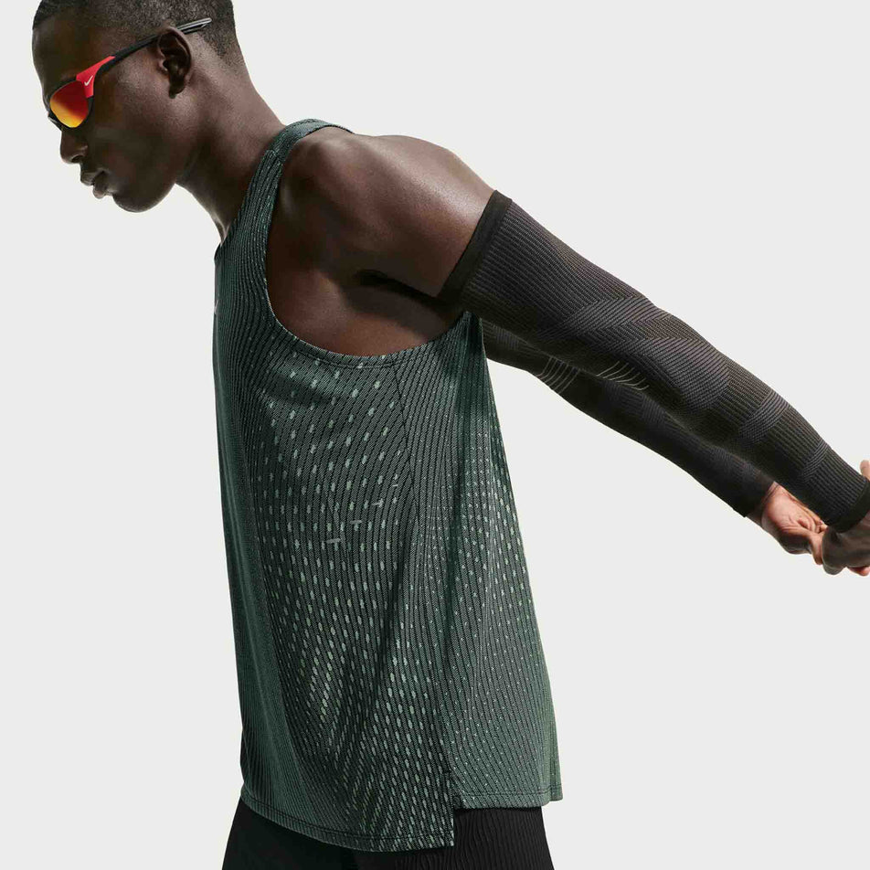 Angled view of a model wearing the Nike Men's Stride Aero-FIT Running Tank Top in the Black/Light Green Spark/Reflective Silver colourway.