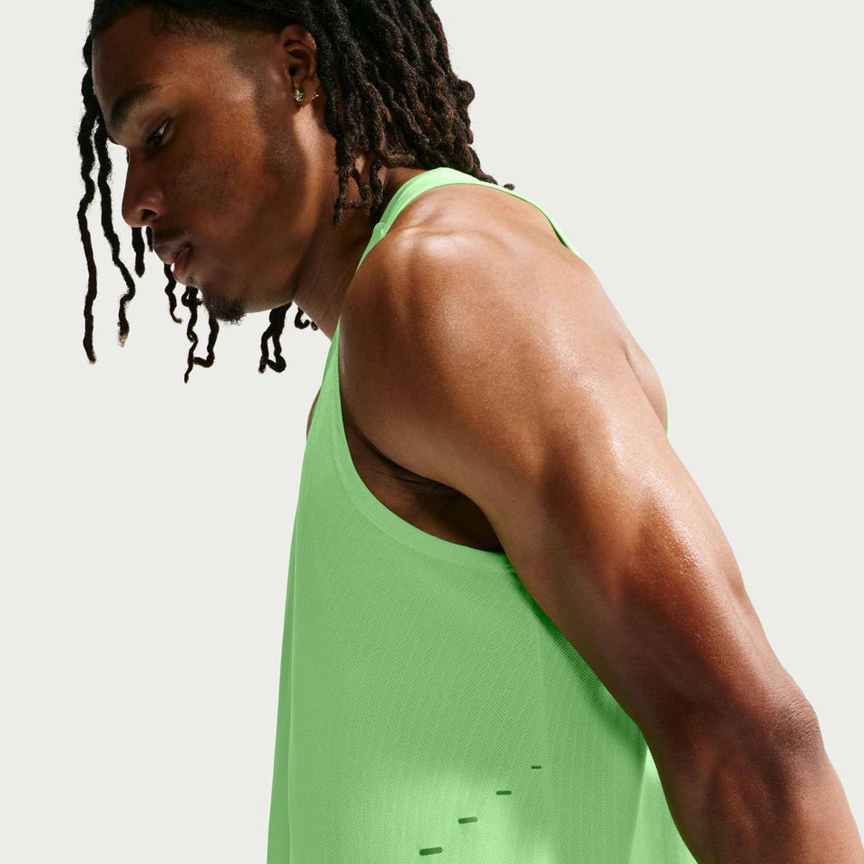 Side view of a model wearing the Nike Men's Stride Aero-FIT Running Tank Top in the Volt/Light Silver/Reflective Silver colourway.