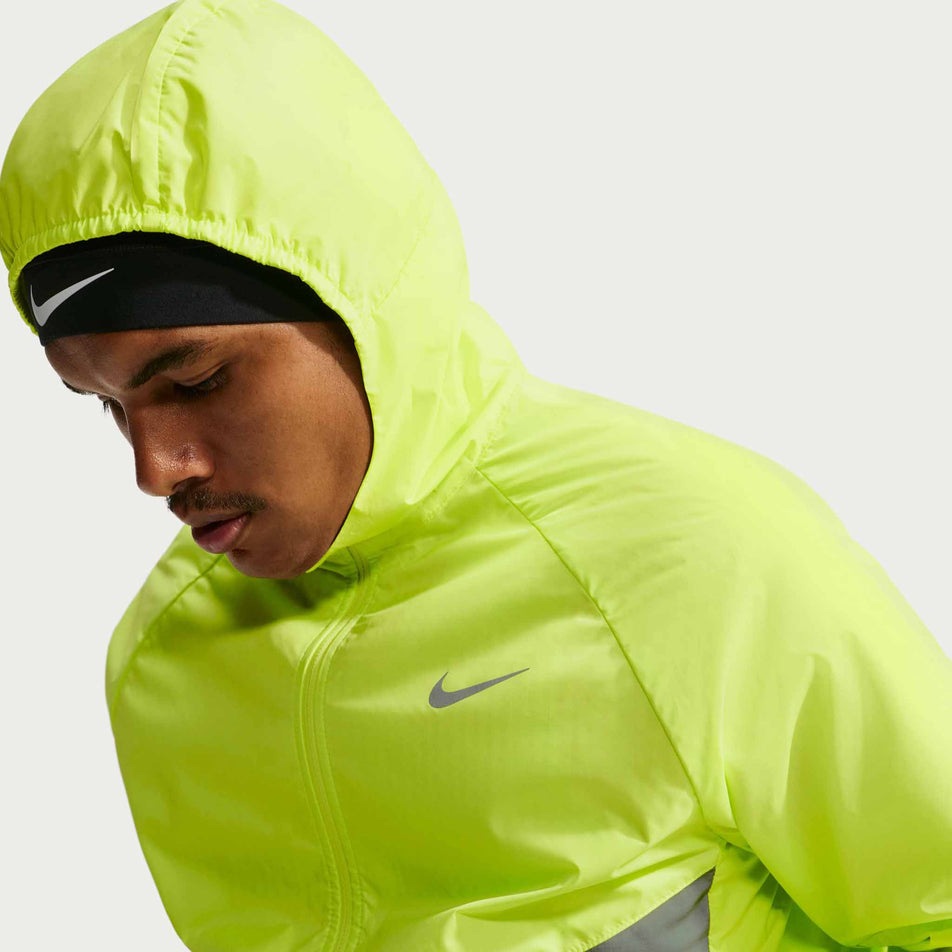 Angled view of a model wearing the Nike Men's Miler Therma-FIT Repel Winterized Running Jacket in the Light Lemon Twist colourway.