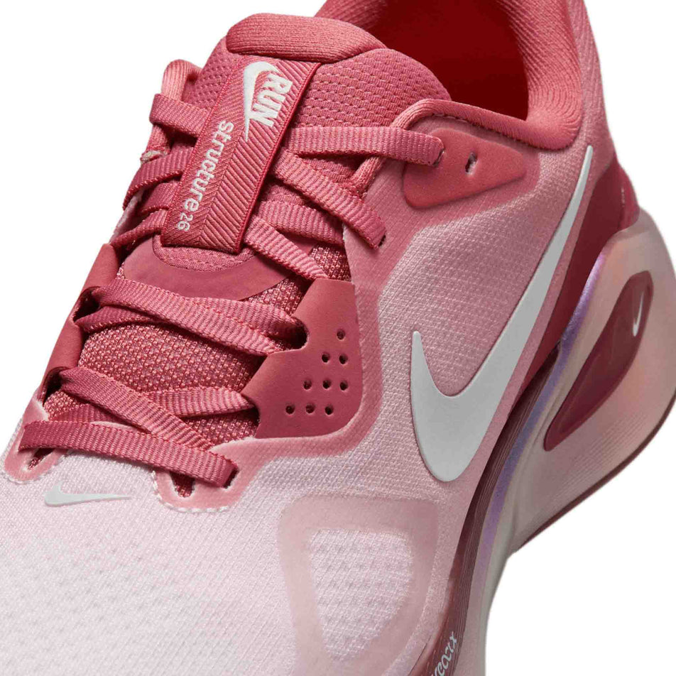 Close-up view of the upper of the left shoe from a pair of Nike Women's Structure 26 Road Running Shoes in the Light Redwood/Barely Green-Team Red colourway.