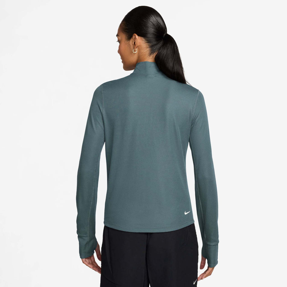 Back view of a model wearing the Nike Women's ACG Dri-FIT 1/2-Zip Trail Running Top in the Mineral Slate/Summit White colourway.