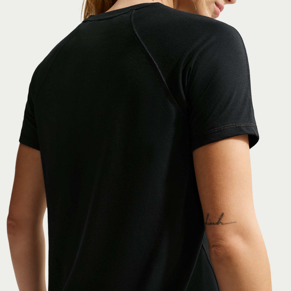 Back view of a model wearing the Nike Women's ACG Dri-FIT Short-Sleeve Trail Running Top in the Black/Summit White colourway.