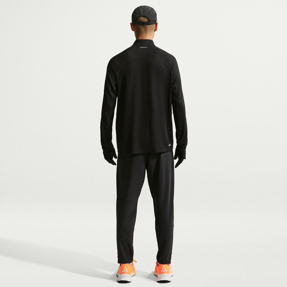 Back view of a model wearing the Nike Men's ACG Dri-FIT Mid-Layer 1/4-Zip Trail Running Top in the Black/Black/Summit White colourway.