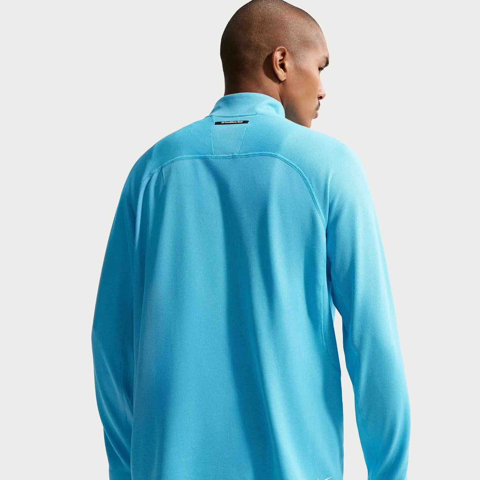 Back view of a model wearing the Nike Men's ACG Dri-FIT Mid-Layer 1/4-Zip Trail Running Top in the Baltic Blue/Baltic Blue/Summit White colourway.