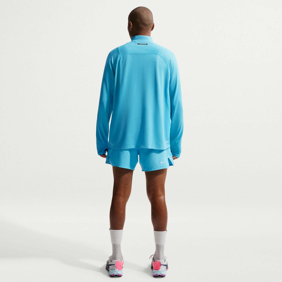 Back view of a model wearing the Nike Men's ACG Dri-FIT Mid-Layer 1/4-Zip Trail Running Top in the Baltic Blue/Baltic Blue/Summit White colourway.
