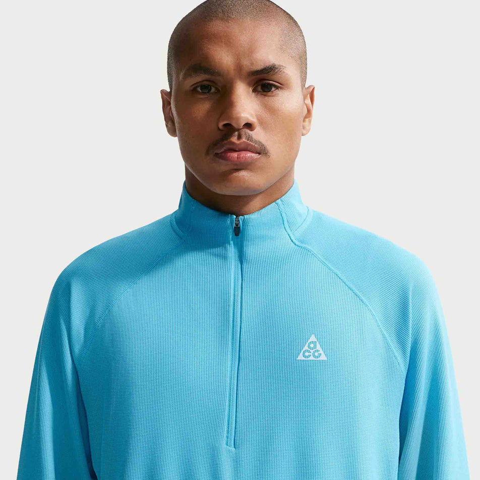 Front view of a model wearing the Nike Men's ACG Dri-FIT Mid-Layer 1/4-Zip Trail Running Top in the Baltic Blue/Baltic Blue/Summit White colourway.