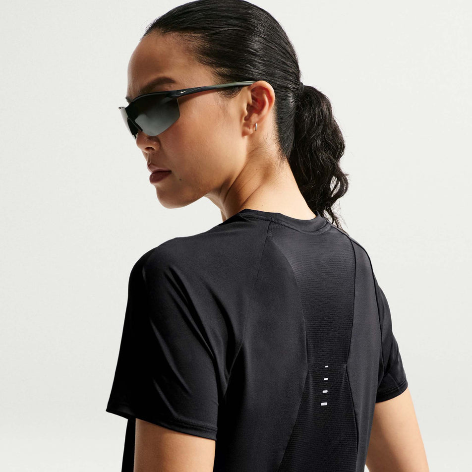 Back view of a model wearing the Nike Women's Swift Dri-FIT Short-Sleeve Running Top in the Black/Reflective Silver colourway.
