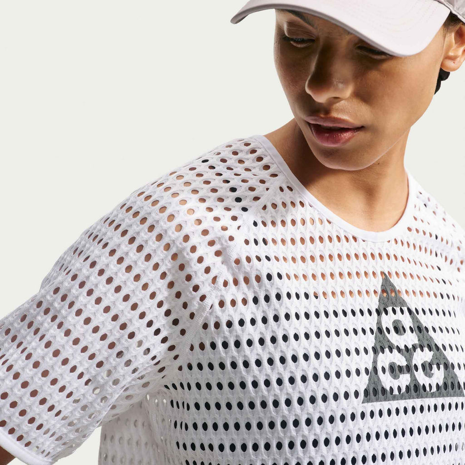 Angled view of a model wearing the Nike Women's ACG Radical AirFlow Dri-FIT Short-Sleeve Trail Running Top in the White/Anthracite colourway.