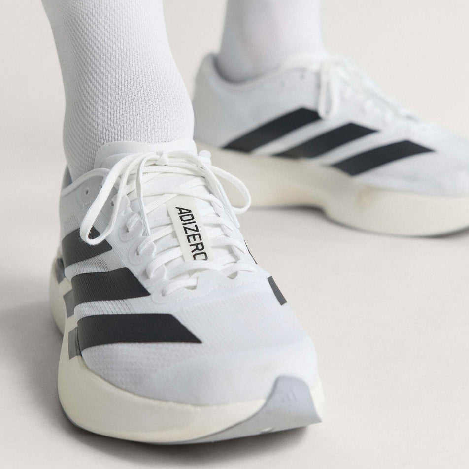 A model wearing a pair of adidas Men's Adizero EVO SL Running Shoes in the Ftwr White/Core Black/Ftwr White colourway.