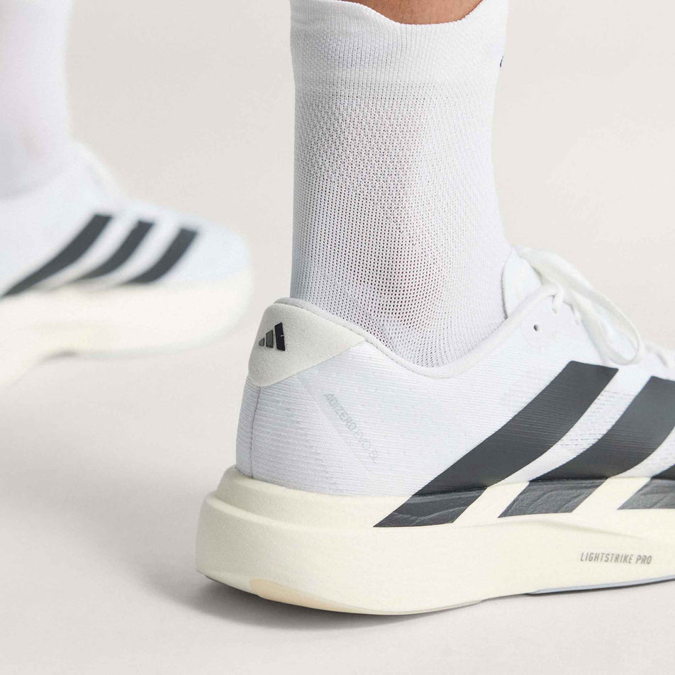A model wearing a pair of adidas Men's Adizero EVO SL Running Shoes in the Ftwr White/Core Black/Ftwr White colourway.