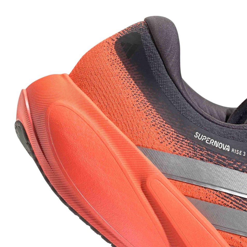 Close-up view of the rearfoot of the right shoe from a pair of adidas Men's Supernova Rise 3 Running Shoes in the Aurora Onix/Silver met./Lucid Orange colourway.
