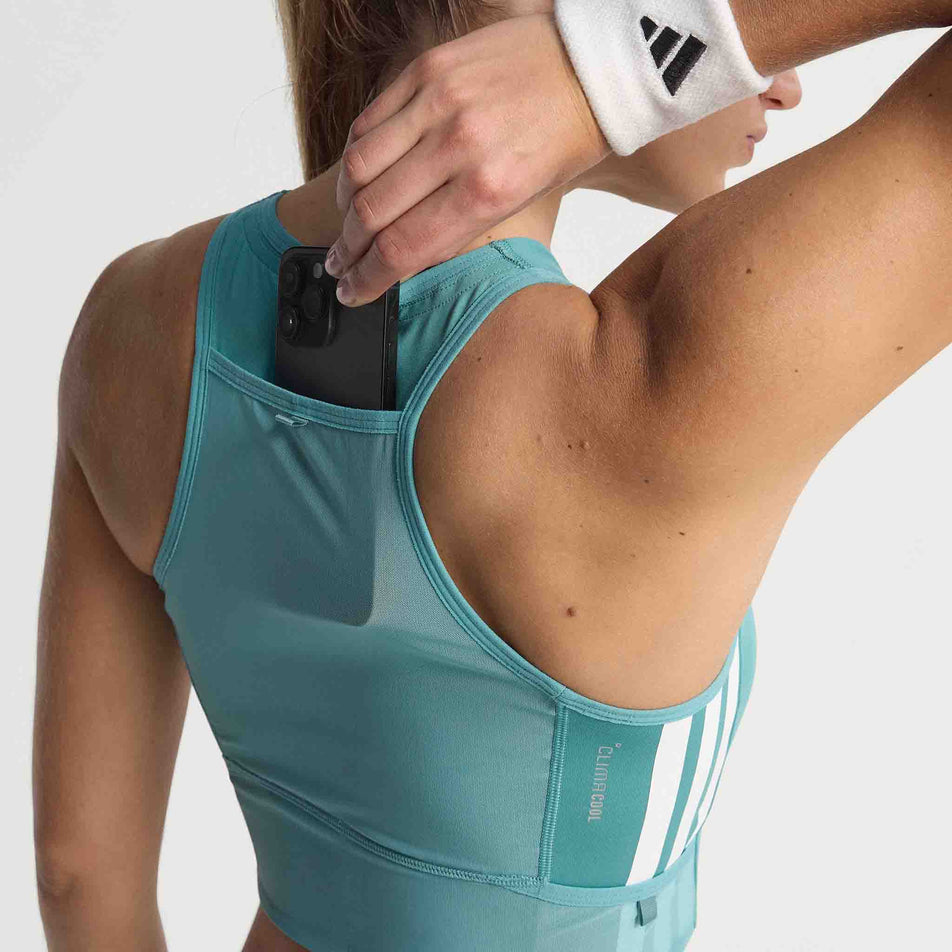 A model demonstrating the pocket on the back of the adidas Women's Adizero Crop in the Powder Teal colourway. (8665221529762)