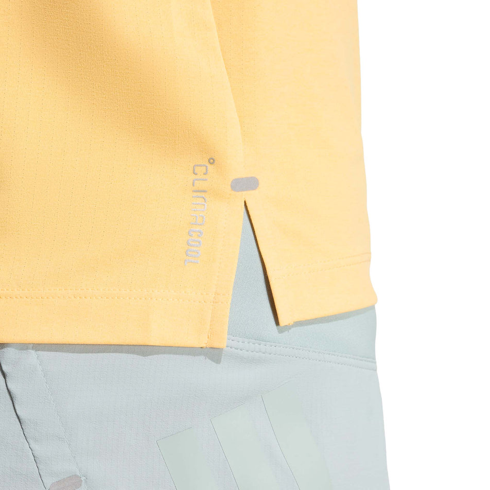 Close-up view of the side split on the hem of the adidas Women's adi365 Tee in the Semi Ice Tangerine colourway.