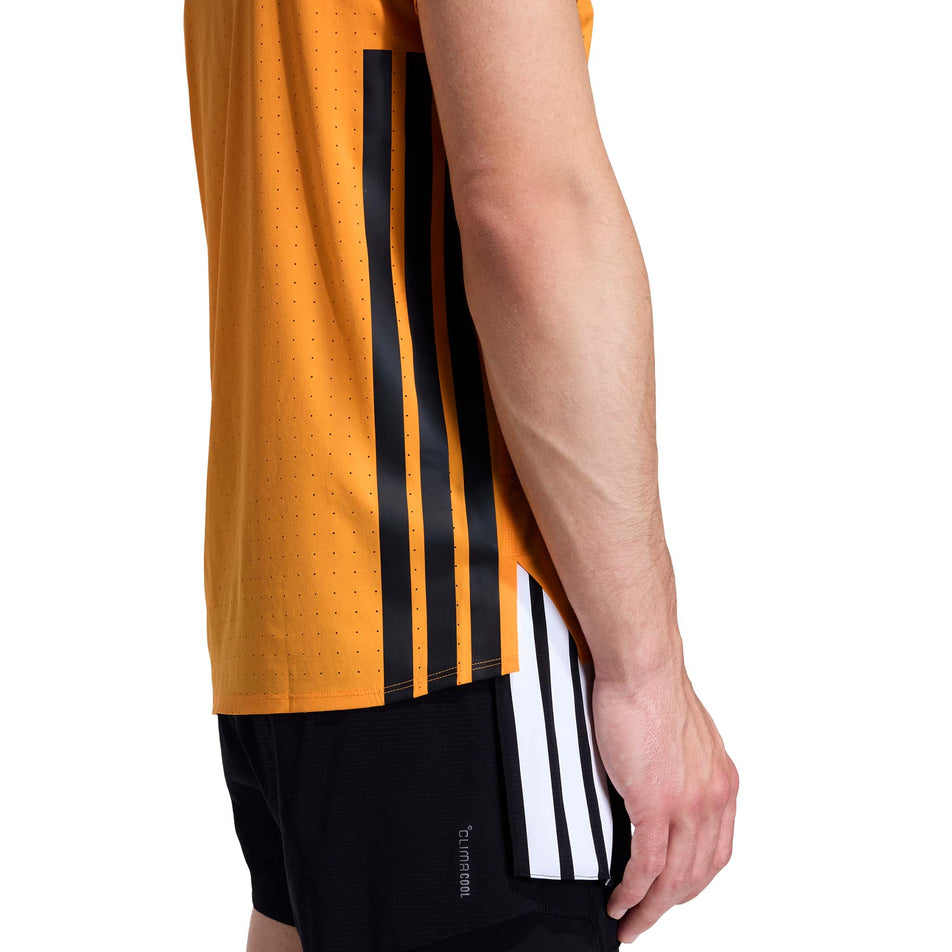 Side view of a model wearing the adidas Men's Adizero Tee in the Pure Tangerine colourway.