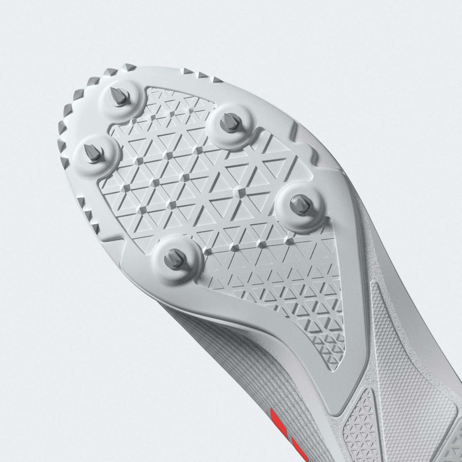 The outsole of the left shoe from a pair of adidas Junior-Unisex Allroundstar Running Spikes in the Ftwr White/Solar Turbo/Gold Met. colourway.