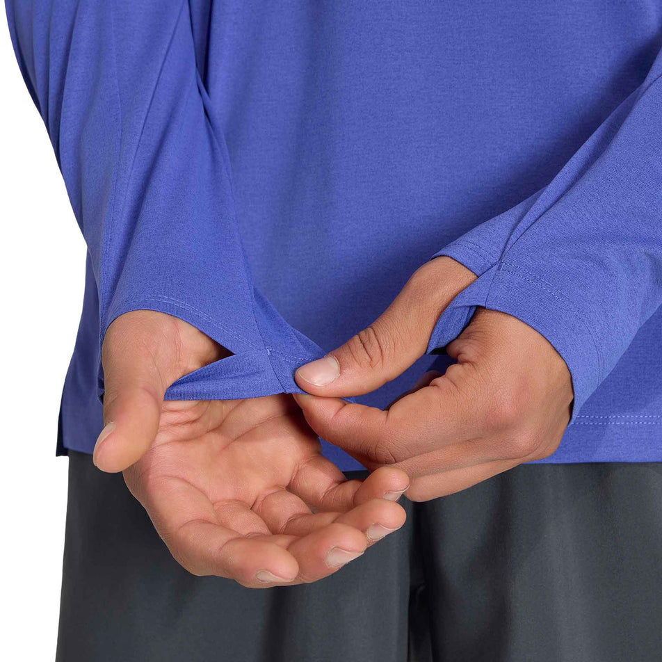 A model demonstrating the thumb loops on the adidas Men's adi365 Long Sleeve Running Top in the Dual Indigo. colourway.