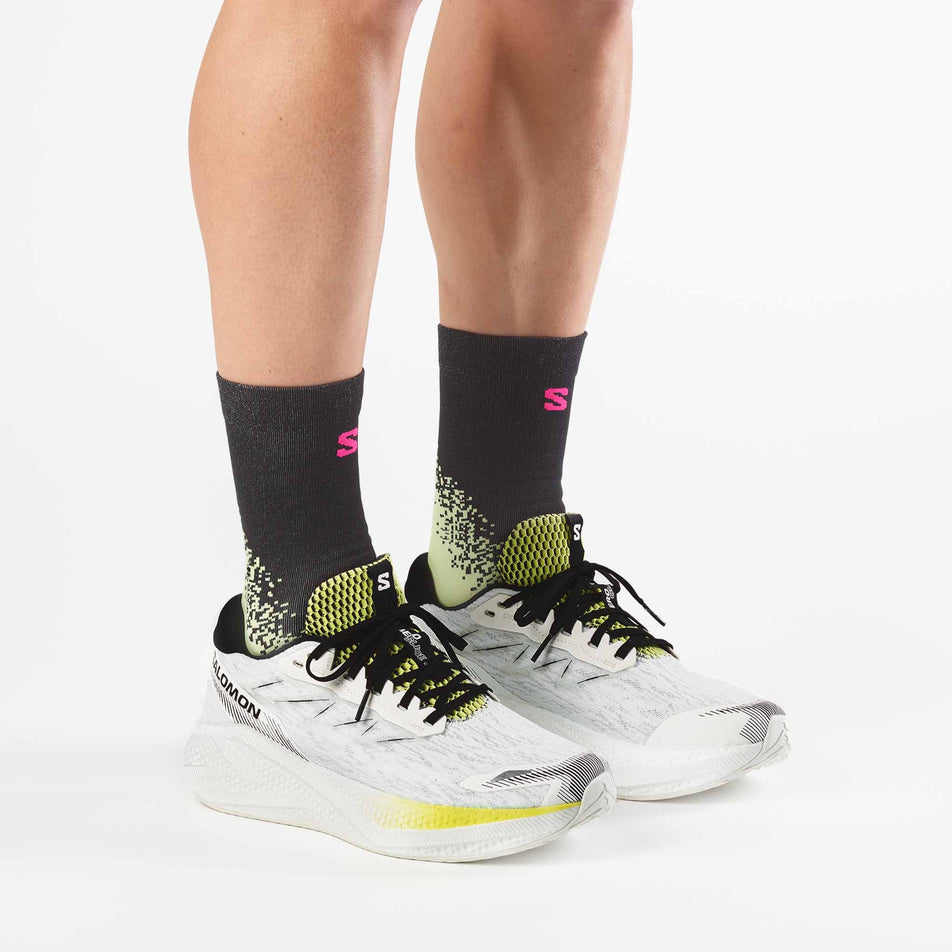 A model wearing a pair of Salomon Men's Aero Glide 4 Running Shoes in the White/Sunny Lime colourway.